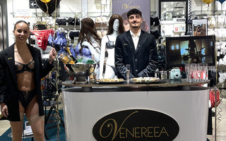Verkaufsfläche Lingerie, Eine Dame in Unterwäsche mit Blazer und ein Herr im Anzug stehen ebenfalls auf der Verkaufsfläche. Zu sehen ist auch ein kleiner Apéro
